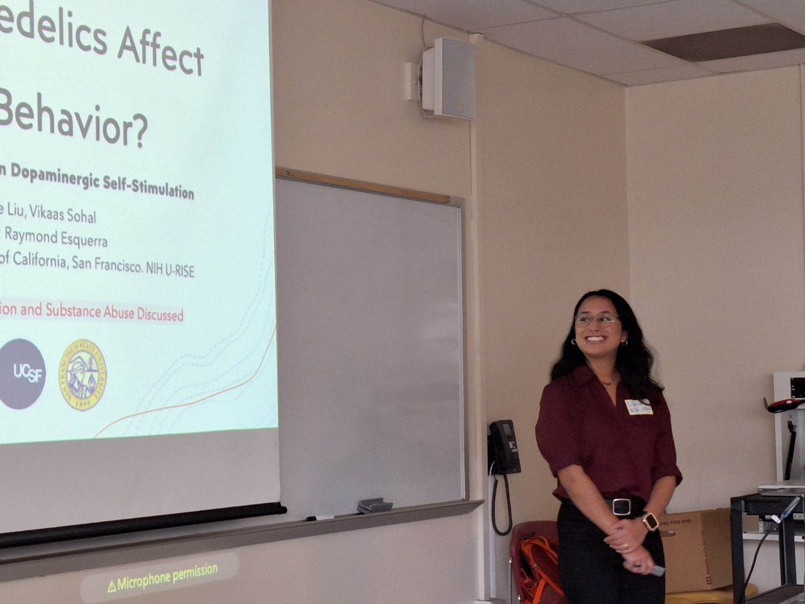 Student stands near opening slide of presentation