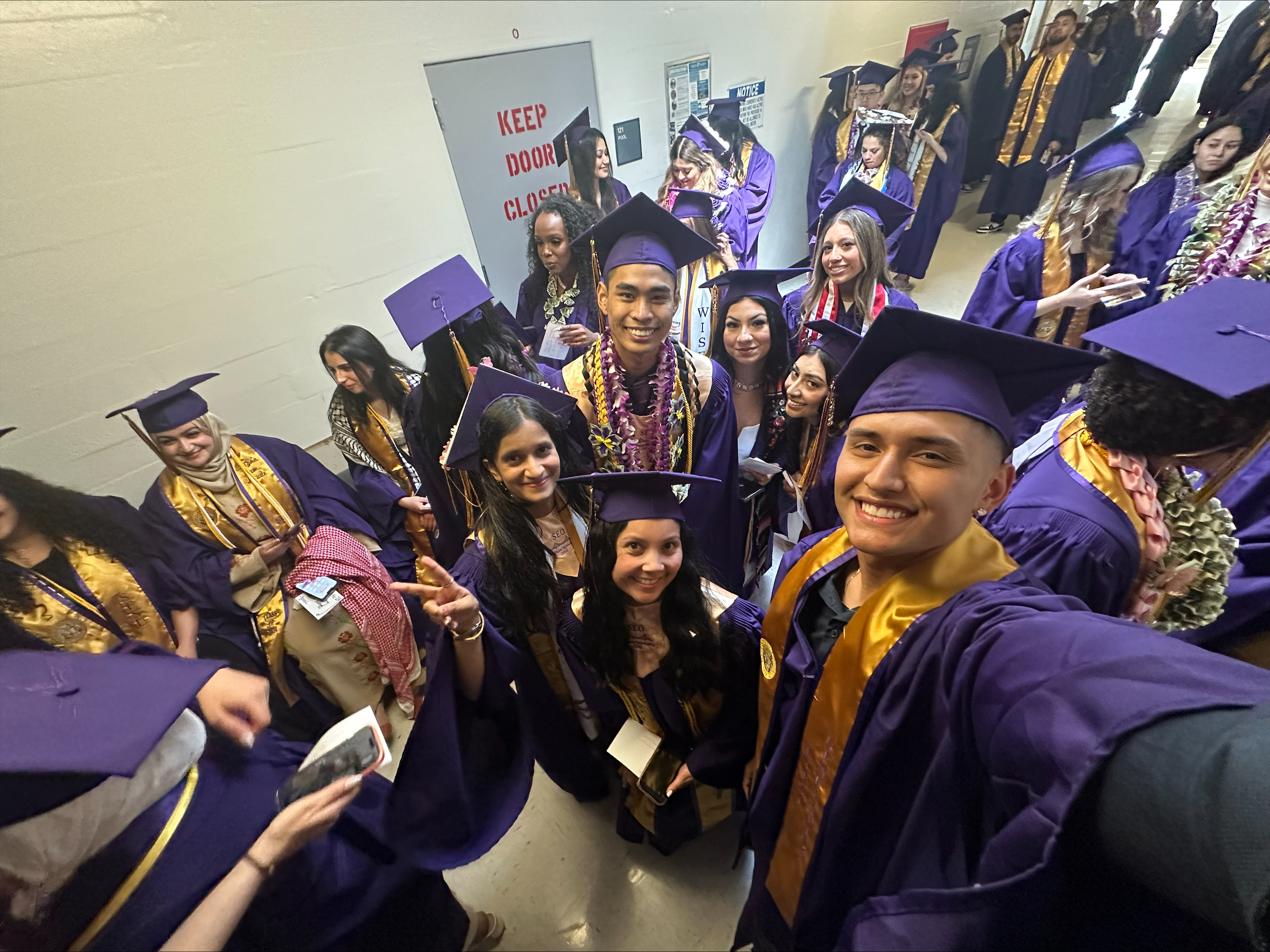 SEO scholars Fayeeza Shaikh, Keezean Paguio, Jalena Zapanta, Fernando Nungaray, and Brianna Rojas-Lobos smile for selfie while waiting for the graduaton ceremony to begin