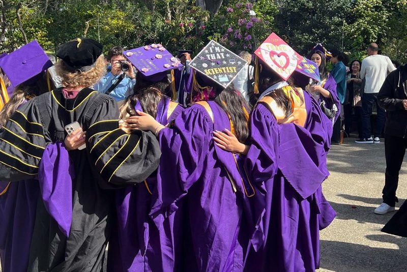 Graduates with decorated graduation caps; one that reads "I'm that scientist"