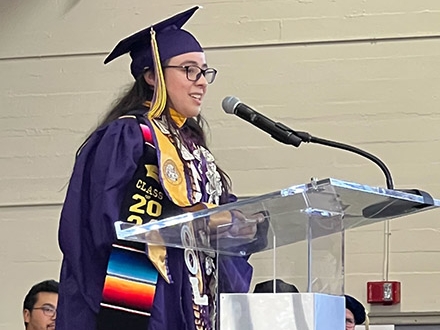 SEO Scholar Marisol Flores giving a speech in her graduation regalia.